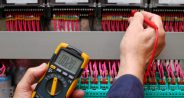 Technician testing a control panel wiht measurement instrument, close-up